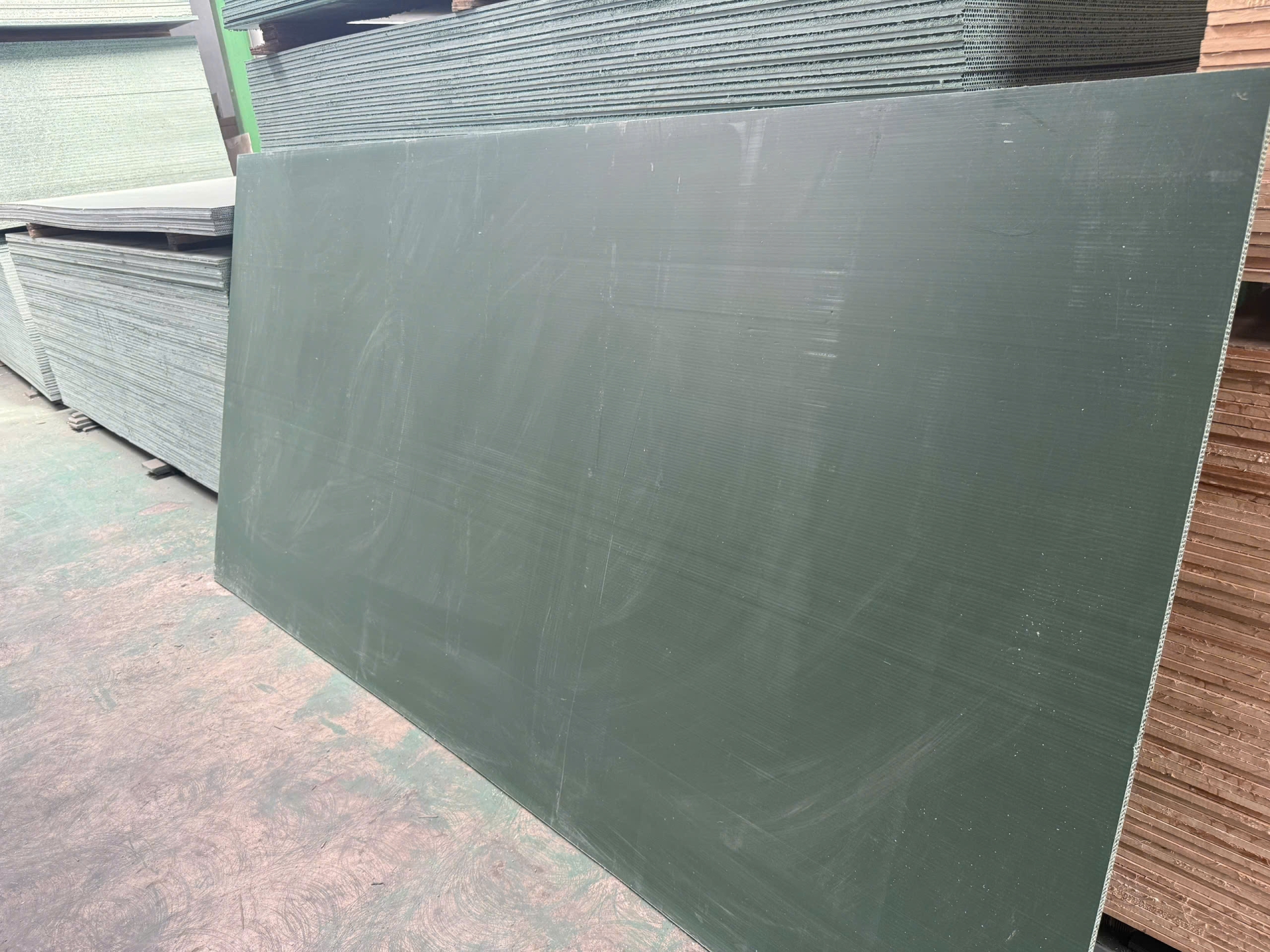Tấm nhựa lót sàn khổ lớn dựng cạnh chồng tấm xi măng sợi tại kho vật liệu