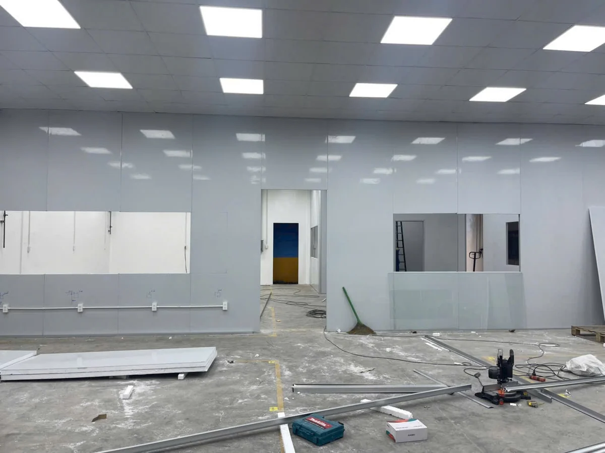 Đội thi công đang ghép tấm panel làm vách và trần trong nhà máy, tấm chờ lắp đặt trên sàn
